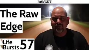 A bald man who looks like our interview subject stairs into the camera with a melancholic emotion, with the lights of a desert prison in the background.